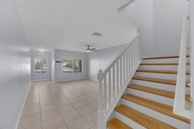 stairway with a ceiling fan, tile patterned flooring, visible vents, and baseboards