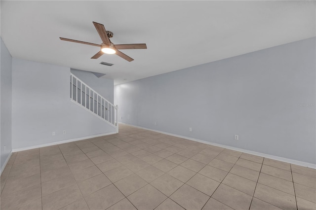 empty room featuring baseboards, visible vents, stairway, and a ceiling fan