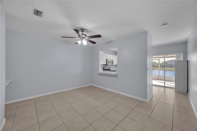 empty room featuring a ceiling fan, visible vents, a water view, and baseboards