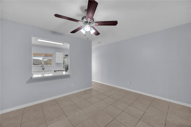 empty room with a ceiling fan, a sink, and baseboards