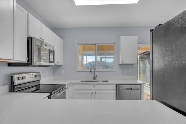 kitchen featuring white cabinetry, stainless steel appliances, a sink, and light countertops