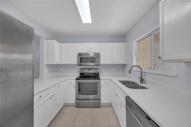 kitchen with light tile patterned floors, light countertops, appliances with stainless steel finishes, white cabinets, and a sink