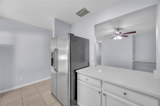 kitchen with stainless steel fridge, visible vents, white cabinets, light countertops, and light tile patterned flooring