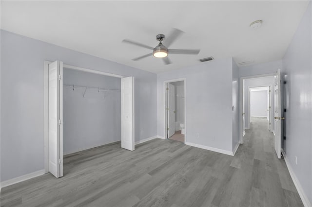 unfurnished bedroom featuring a closet, wood finished floors, visible vents, and baseboards