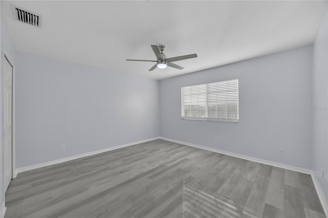 empty room with visible vents, ceiling fan, baseboards, and wood finished floors