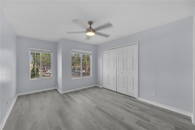 unfurnished bedroom with a closet, ceiling fan, baseboards, and wood finished floors