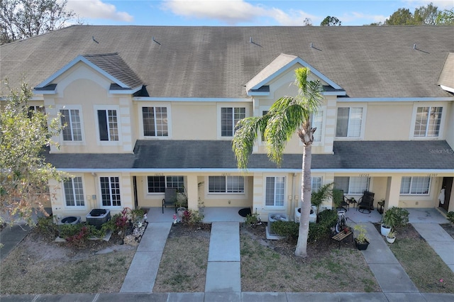 townhome / multi-family property featuring roof with shingles and stucco siding