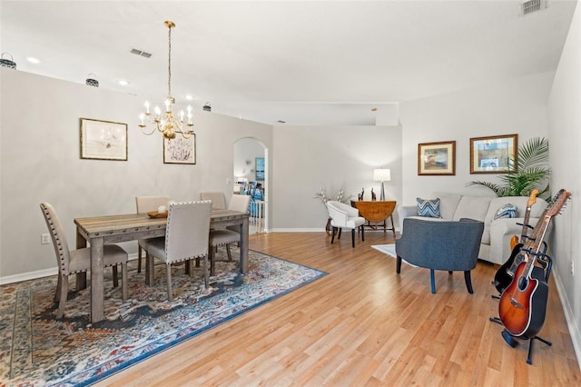 dining room with arched walkways, visible vents, baseboards, and wood finished floors