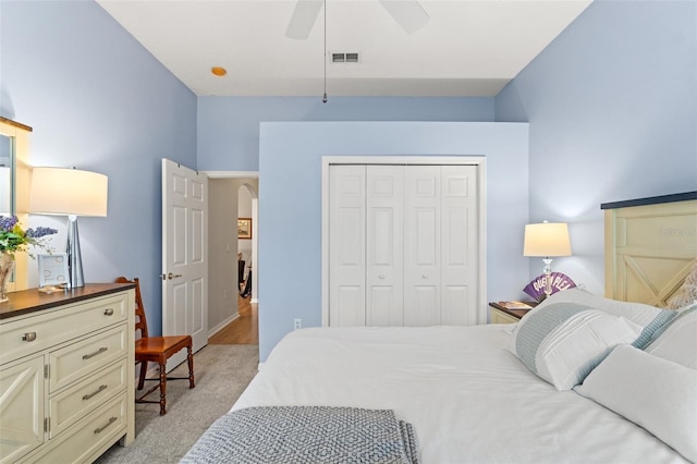 bedroom featuring light carpet, visible vents, arched walkways, a ceiling fan, and a closet