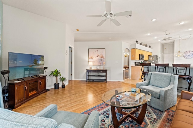 living area with light wood-style flooring, recessed lighting, ceiling fan with notable chandelier, visible vents, and baseboards