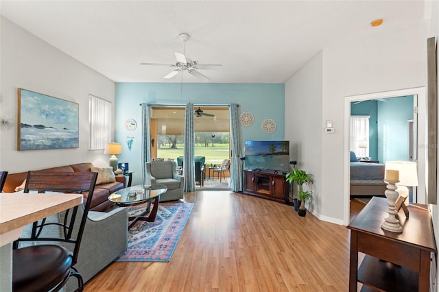 living area featuring light wood finished floors, baseboards, and a ceiling fan