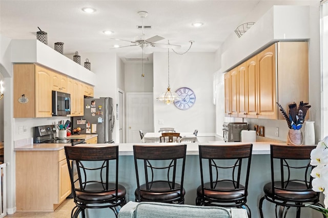 kitchen featuring light brown cabinets, stainless steel appliances, a breakfast bar, a peninsula, and visible vents