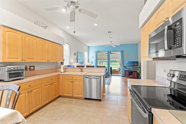 kitchen with stainless steel appliances, a peninsula, a sink, and light countertops