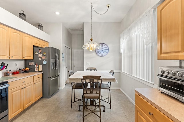 kitchen with a toaster, appliances with stainless steel finishes, light brown cabinetry, pendant lighting, and a notable chandelier