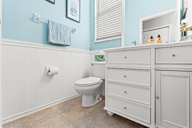 bathroom with tile patterned flooring, a wainscoted wall, vanity, and toilet