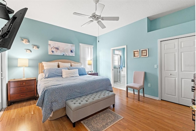 bedroom with a ceiling fan, baseboards, light wood-style floors, a closet, and ensuite bath