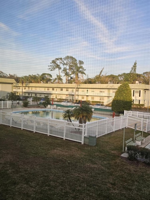 pool with a yard, a water view, and fence