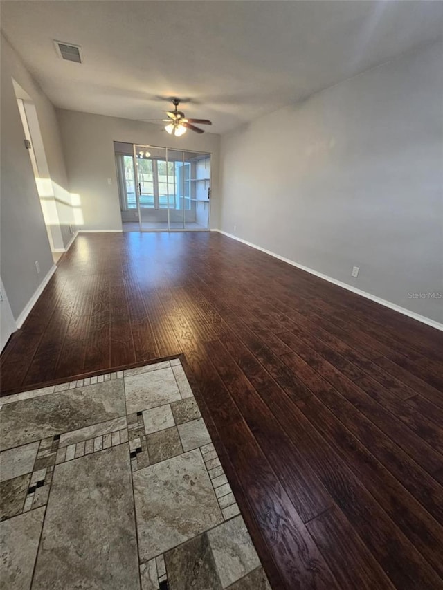 empty room featuring a ceiling fan, baseboards, visible vents, and hardwood / wood-style floors