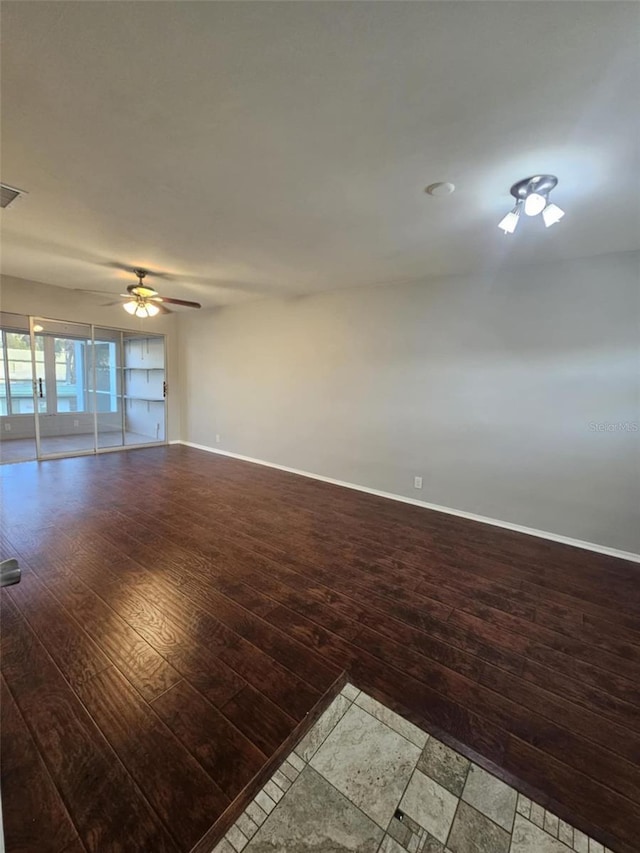 unfurnished room featuring a ceiling fan, visible vents, baseboards, and hardwood / wood-style floors