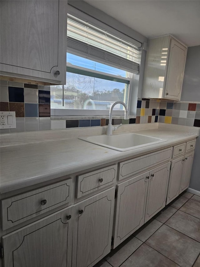 kitchen with light tile patterned floors, backsplash, a sink, and light countertops