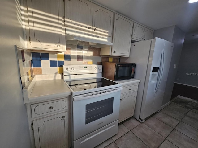 kitchen featuring light tile patterned floors, under cabinet range hood, white appliances, light countertops, and tasteful backsplash