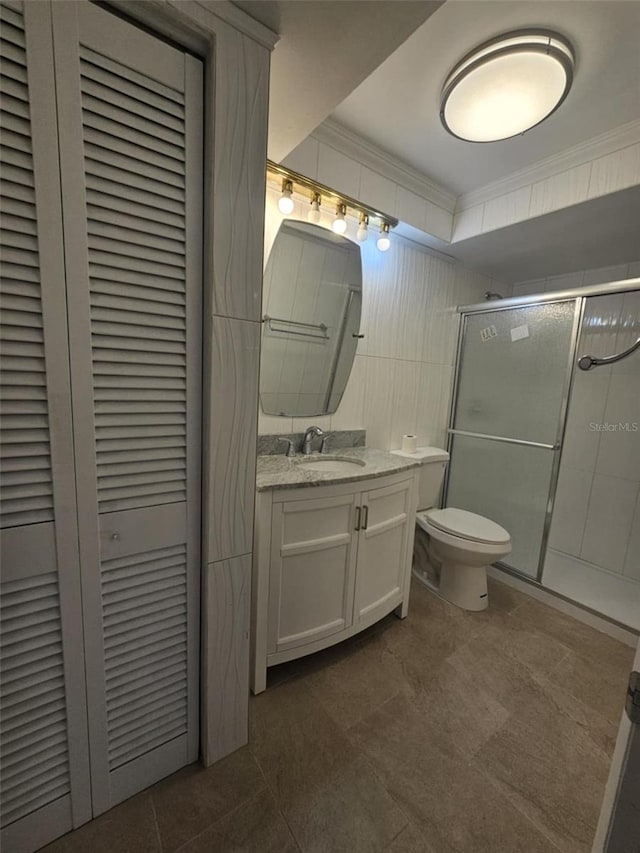 bathroom featuring toilet, ornamental molding, vanity, a shower stall, and a closet