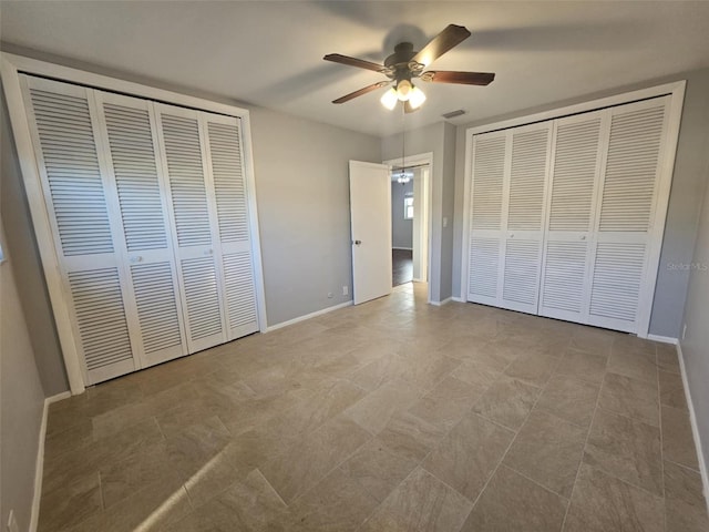 unfurnished bedroom featuring a ceiling fan, two closets, visible vents, and baseboards