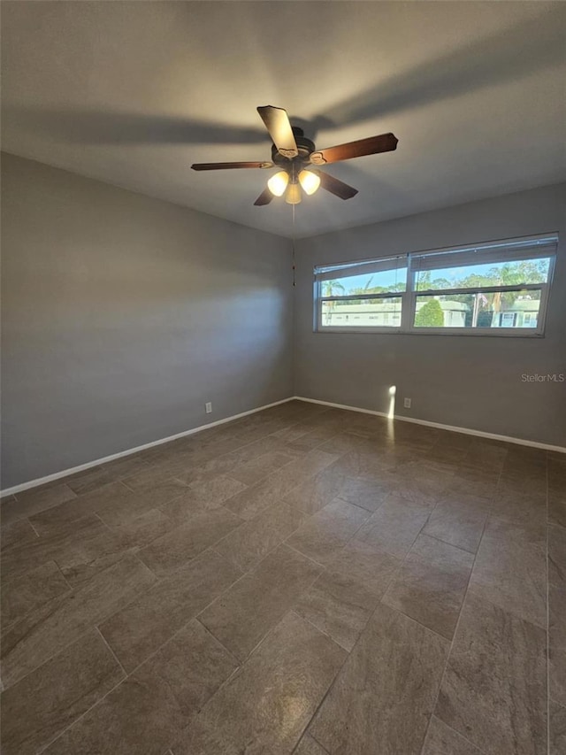 unfurnished room with a ceiling fan and baseboards