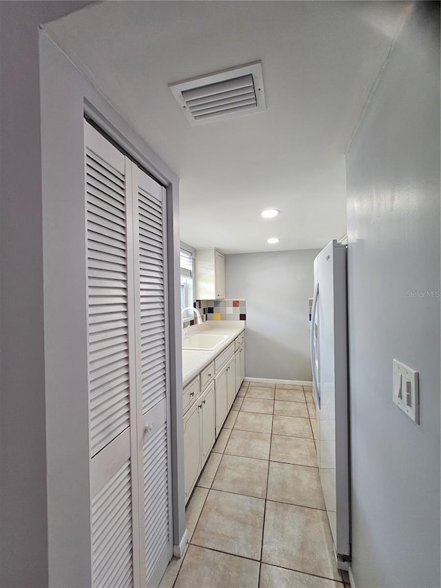 1433 S Belcher Rd Unit A12, Clearwater, FL 33764 - kitchen with a sink, freestanding refrigerator, light countertops, white cabinetry, and baseboards