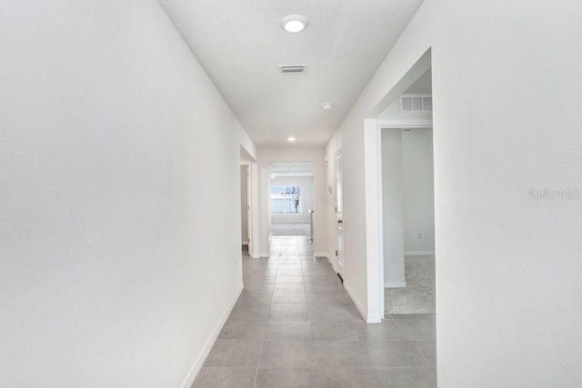 hall with baseboards, visible vents, and tile patterned flooring