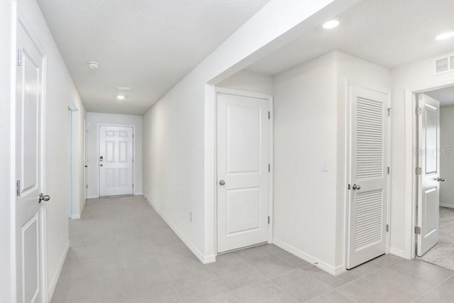 corridor featuring light tile patterned floors, recessed lighting, visible vents, and baseboards