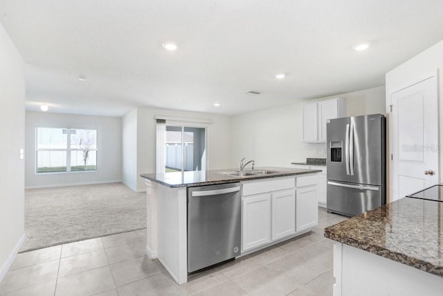 kitchen with appliances with stainless steel finishes, a center island with sink, a sink, and white cabinetry