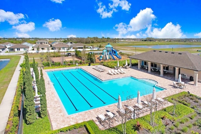 community pool featuring playground community, a patio area, and a water view