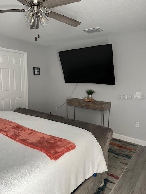 bedroom with visible vents, wood finished floors, baseboards, and ceiling fan