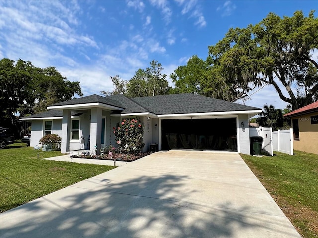 view of front of house with a front yard, fence, driveway, stucco siding, and a garage