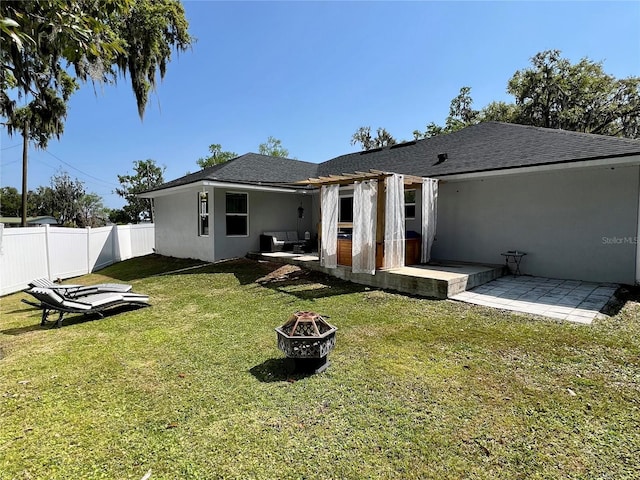 back of house featuring a fire pit, fence, stucco siding, a yard, and a patio area