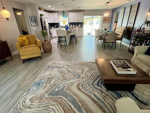 living area featuring recessed lighting, light wood-type flooring, and baseboards