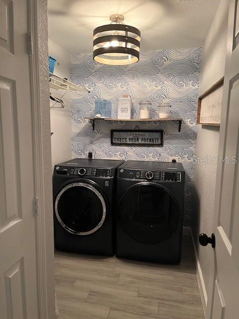 laundry area featuring washer and clothes dryer, laundry area, a chandelier, and light wood-style floors