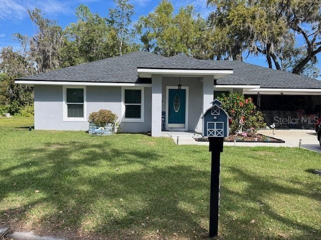 ranch-style home with stucco siding, a front lawn, and roof with shingles