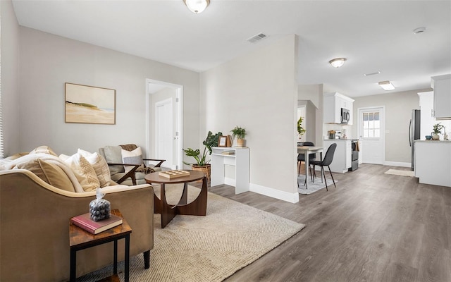 living area featuring wood finished floors, visible vents, and baseboards