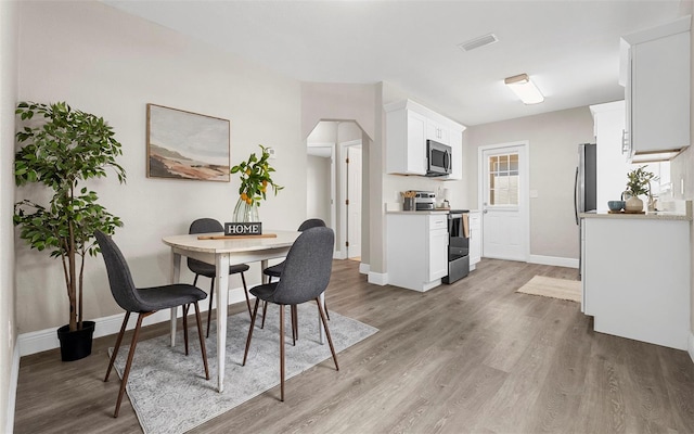 dining area featuring light wood-style floors, baseboards, and visible vents