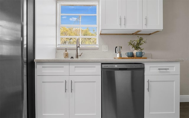 kitchen with light countertops, appliances with stainless steel finishes, a sink, and white cabinets