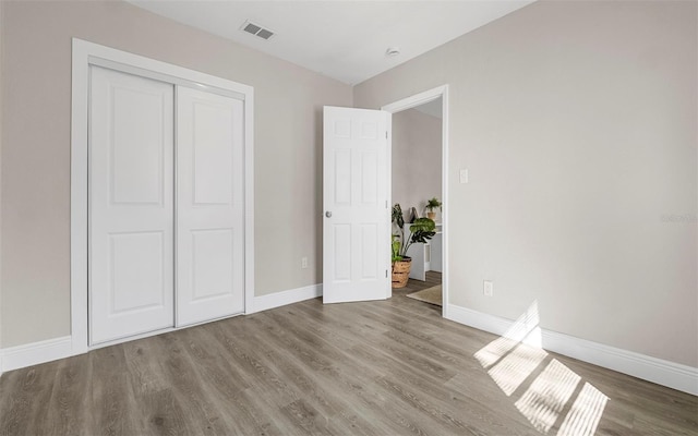 unfurnished bedroom with baseboards, visible vents, and wood finished floors