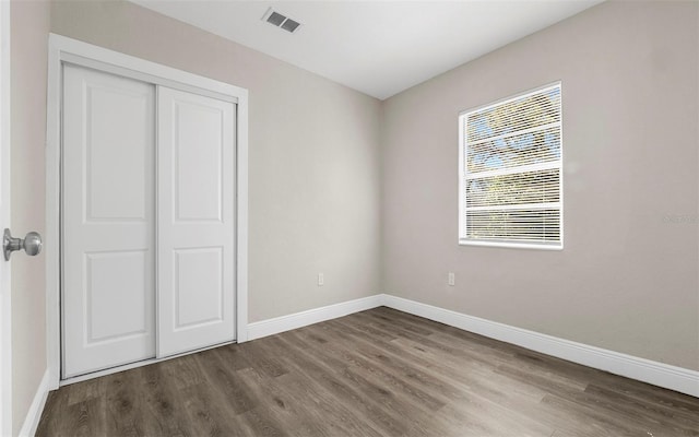 unfurnished bedroom featuring visible vents, baseboards, and wood finished floors