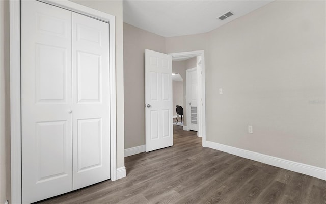 unfurnished bedroom with wood finished floors, visible vents, and baseboards