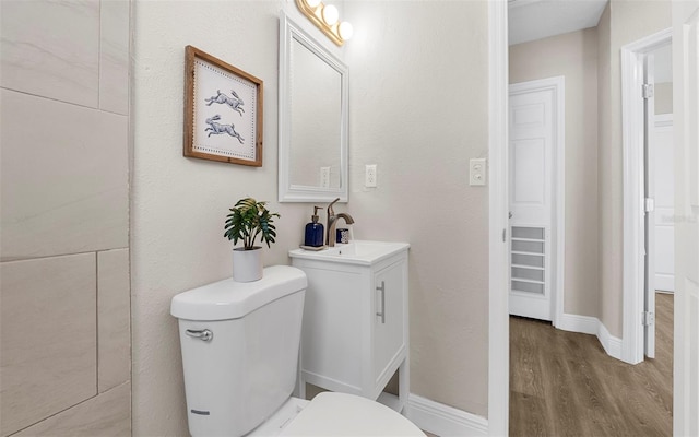 bathroom featuring vanity, wood finished floors, toilet, and baseboards