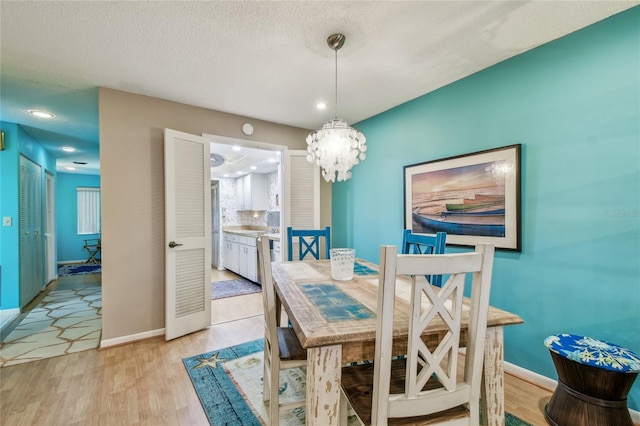 dining area featuring light wood-style floors, baseboards, and a chandelier