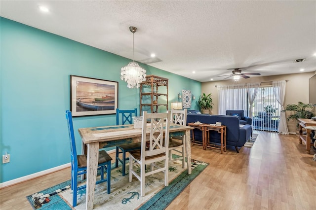 dining area featuring ceiling fan with notable chandelier, a textured ceiling, wood finished floors, recessed lighting, and baseboards