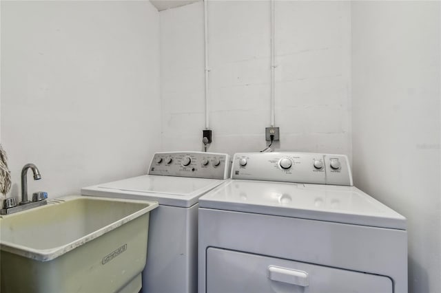 clothes washing area with washer and dryer, laundry area, and a sink