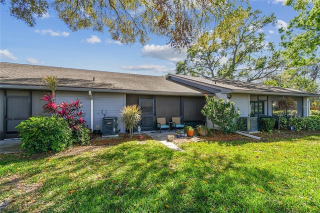 back of property with central AC unit and a lawn